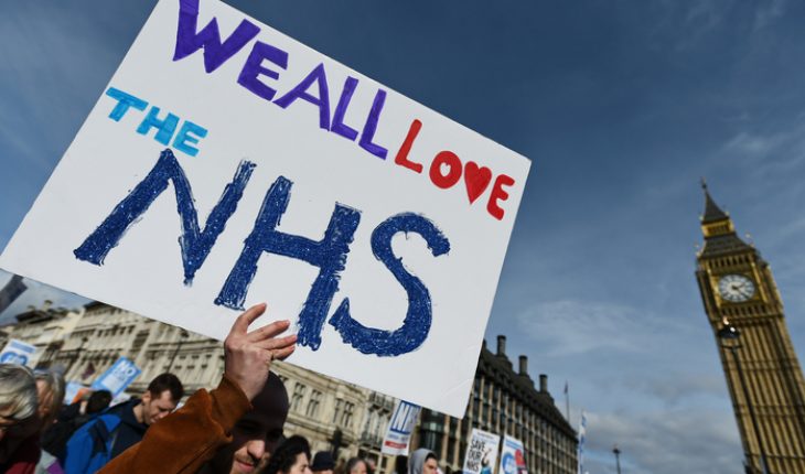Protesters march past Parliament during a demonstration in support of the NHS