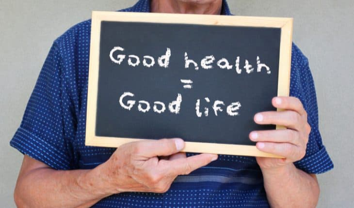 ‹man holding balckboard: good health, good life