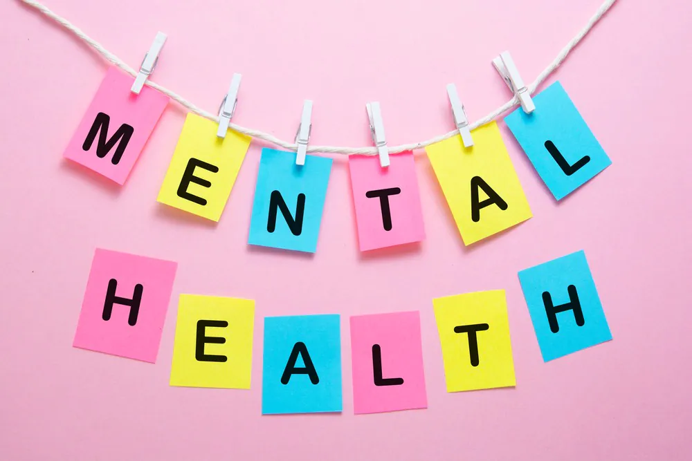 Mental health word writen on colorful sticky notes over pink bright background