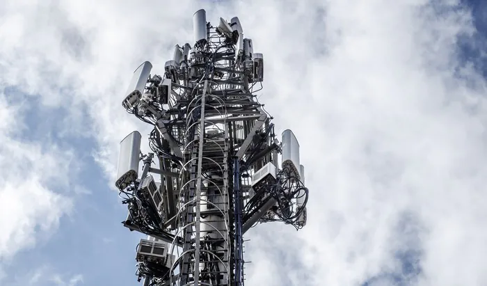 Digital addiction leads to back pain Large Communications Tower on a Blue Sky